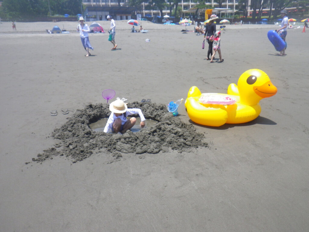 砂浜で砂遊びをする子どもと黄色いアヒル型の浮き輪。伊豆今井浜東急ホテル前のビーチでのファミリー滞在