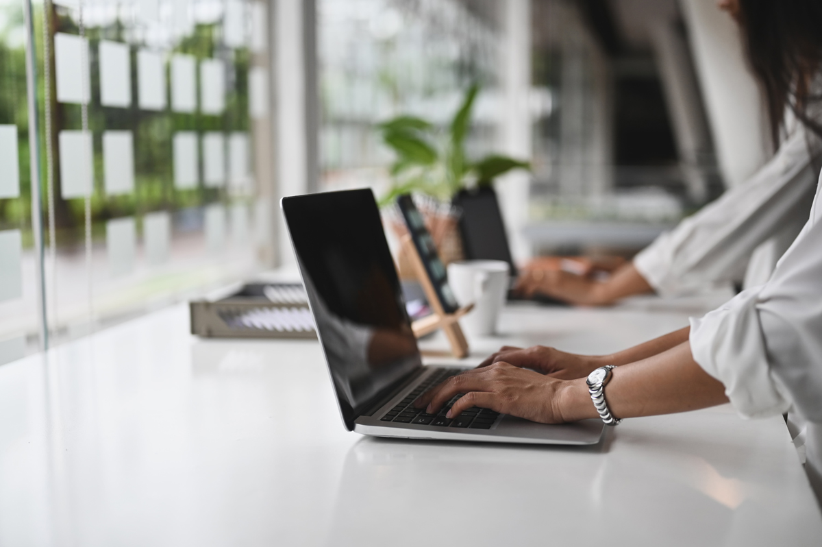 自然光の入るデスクでパソコン作業をする人物（バーチャルオフィスの使用イメージ）