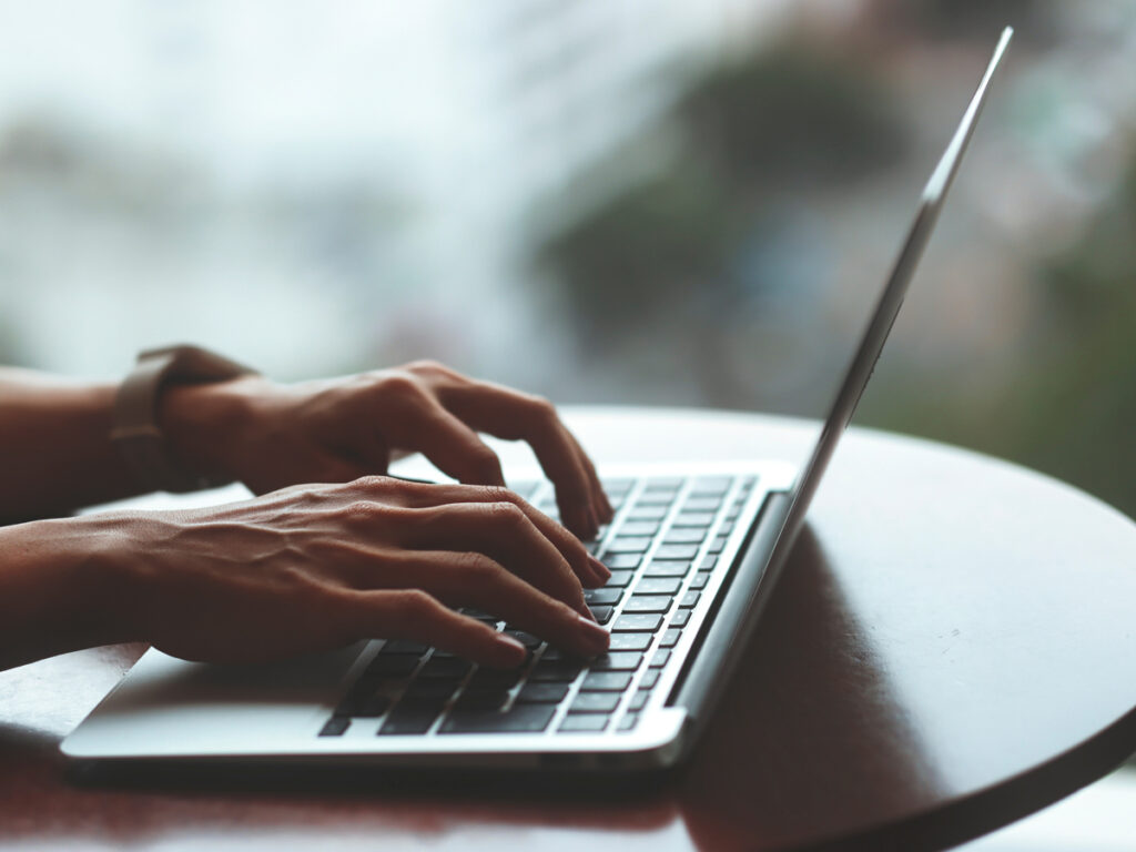 ノートPCのキーボードを素早くタイピングする手元のクローズアップ