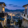 Nagasaki hillside cityscape at twilight with warm-lit houses and valley lights