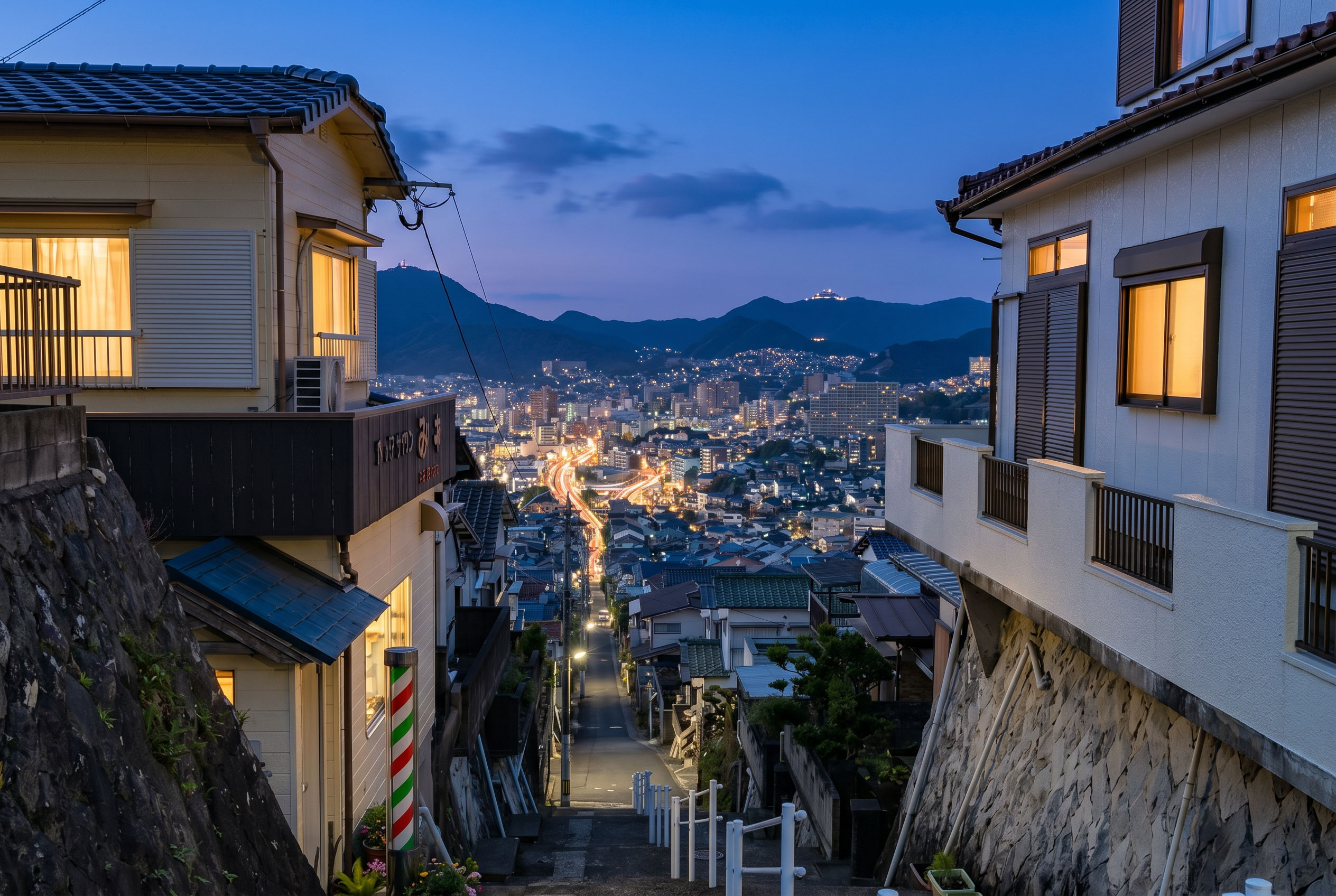 Nagasaki hillside cityscape at twilight with warm-lit houses and valley lights