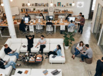 開放的なコワーキングスペースで複数のビジネスパーソンがノートPCで作業している様子